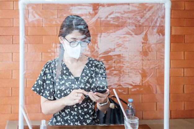 Foto portret van een jonge vrouw die tegen een bakstenen muur staat en een telefoon gebruikt