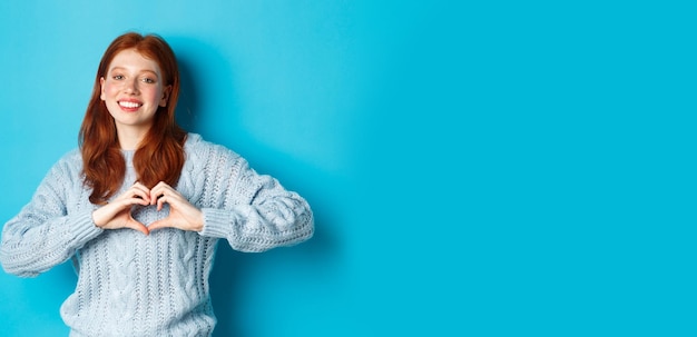 Foto portret van een jonge vrouw die tegen een blauwe achtergrond staat