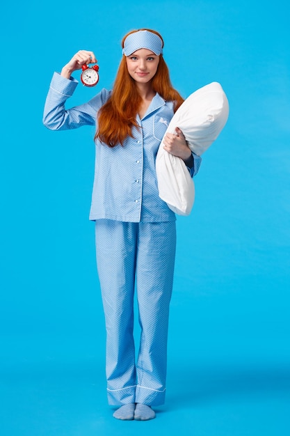 Portret van een jonge vrouw die tegen een blauwe achtergrond staat