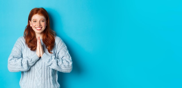 Portret van een jonge vrouw die tegen een blauwe achtergrond staat