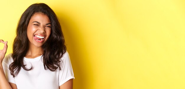 Foto portret van een jonge vrouw die tegen een gele muur staat