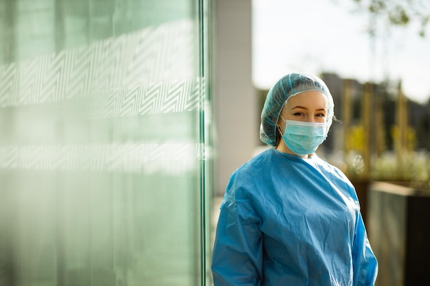 Portret van een jonge vrouw die tegen een glazen muur staat
