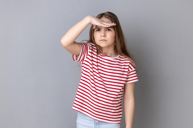 Portret van een jonge vrouw die tegen een grijze achtergrond staat