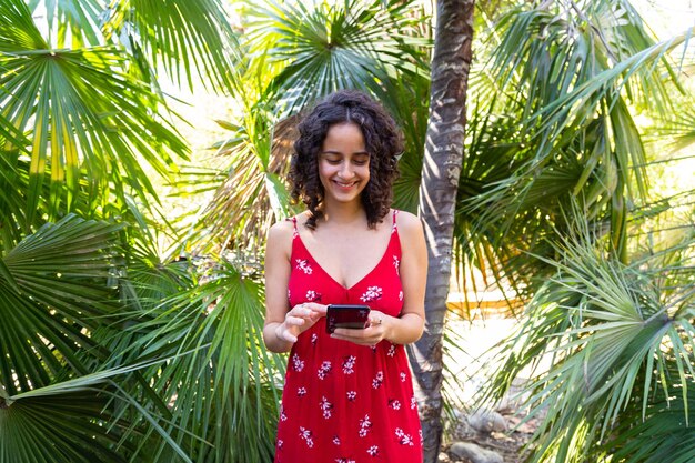 Portret van een jonge vrouw die tegen een palmboom staat