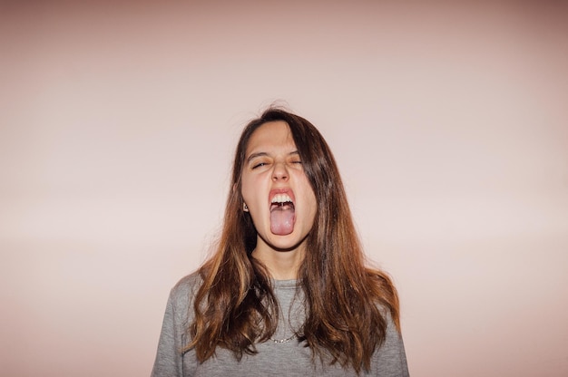 Portret van een jonge vrouw die tegen een roze achtergrond staat