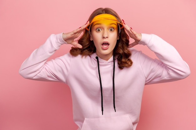 Foto portret van een jonge vrouw die tegen een roze achtergrond staat