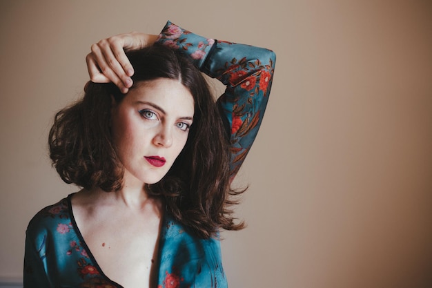 Portret van een jonge vrouw die tegen een witte achtergrond staat