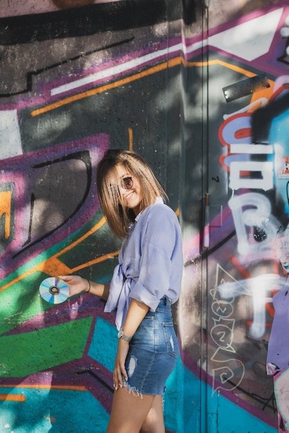 Portret van een jonge vrouw die tegen graffiti staat