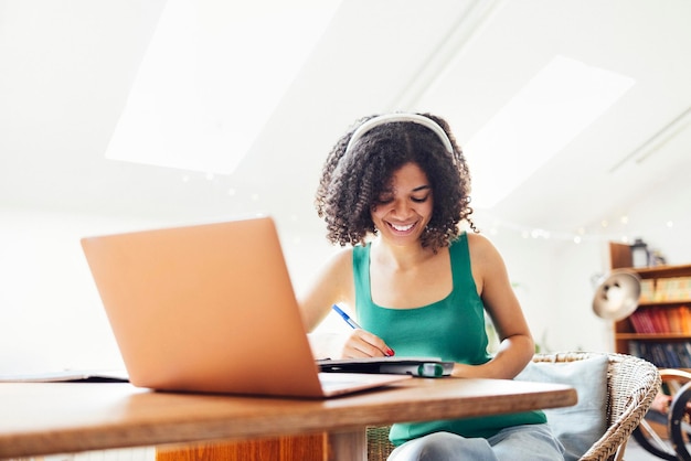 Portret van een jonge vrouw die thuis een laptop gebruikt