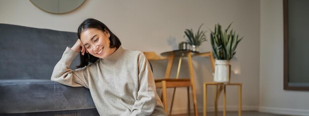 Portret van een jonge vrouw die thuis op de bank zit