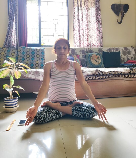 Foto portret van een jonge vrouw die thuis op de vloer zit en yoga doet