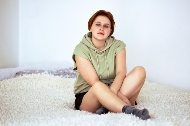 Foto portret van een jonge vrouw die thuis op het bed zit