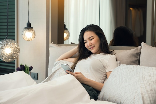 Portret van een jonge vrouw die thuis op het bed zit