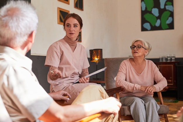 Portret van een jonge vrouw die tijdens de therapiesessie met senioren in het bejaardentehuis praat