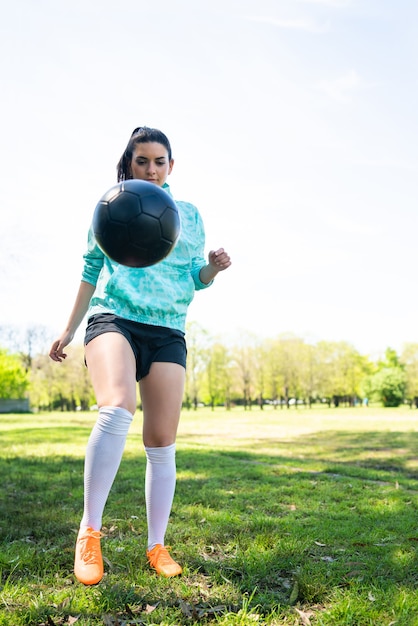 Portret van een jonge vrouw die voetbalvaardigheden oefent en trucs doet met de voetbalbal. Voetballer jongleren met de bal. Sport concept.