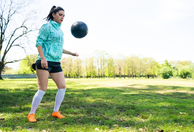 Portret van een jonge vrouw die voetbalvaardigheden oefent en trucs doet met de voetbalbal. Voetballer jongleren met de bal.