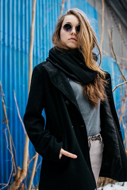 Portret van een jonge vrouw die warme kleding draagt tegen gegolfd ijzer