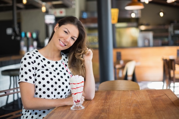 Portret van een jonge vrouw door drankje op tafel zitten