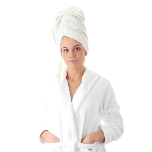 Portret van een jonge vrouw in badjas en handdoek op het hoofd tegen een witte achtergrond