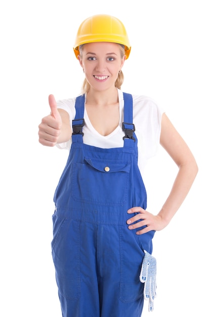 Portret van een jonge vrouw in blauwe bouwer uniform duimschroef opwaarts geïsoleerd op een witte achtergrond