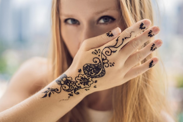 Portret van een jonge vrouw in casual stijl met mehendi tegen de achtergrond van een grote stad