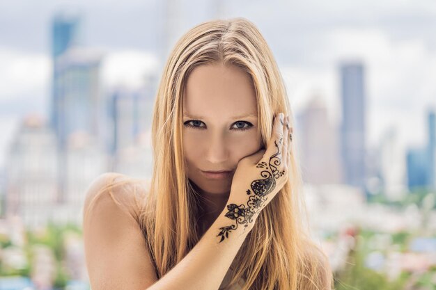 Portret van een jonge vrouw in casual stijl met mehendi tegen de achtergrond van een grote stad