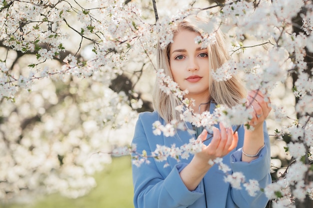 Portret van een jonge vrouw in de bloemrijke tuin in de lente. Amandel bloemen bloeien
