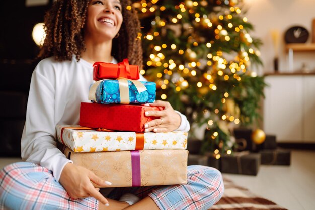 Portret van een jonge vrouw in de hoed van de kerstman met cadeau bij de kerstboom Kerstmis Nieuwjaar