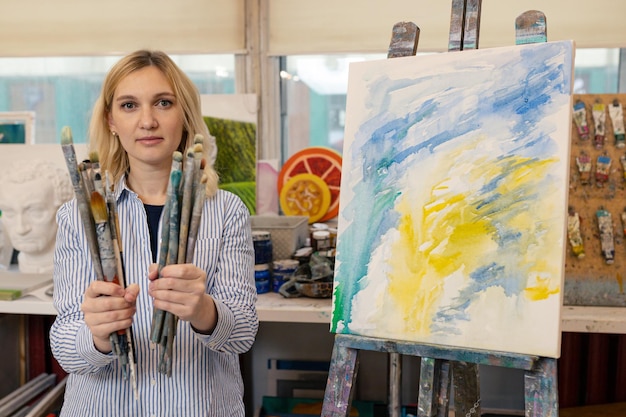 Portret van een jonge vrouw in de studio Een kunstenaar met penselen in een kunstgalerie