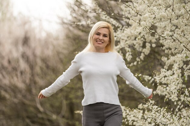 Portret van een jonge vrouw in een bloeiende boomgaard. Blonde vrouw