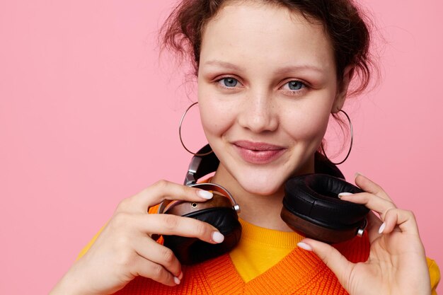 Portret van een jonge vrouw in een oranje trui koptelefoon muziek entertainment bijgesneden weergave ongewijzigd