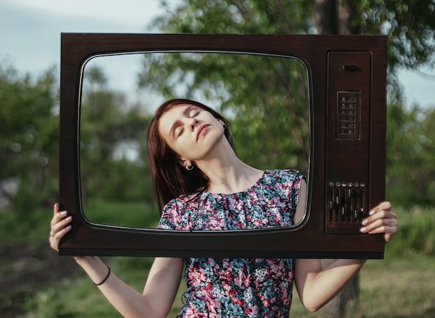 Portret van een jonge vrouw in een oud retro televisieframe met gesloten ogen, technologie en mentale publiciteitsproblemen