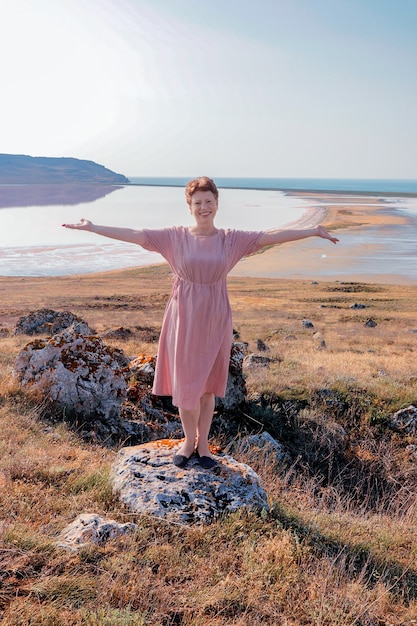 portret van een jonge vrouw in een roze jurk in de velden