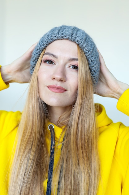 Portret van een jonge vrouw in een wintermuts en een felgele hoodie