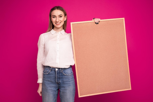 Portret van een jonge vrouw in een wit overhemd met een taakbord op een roze achtergrond