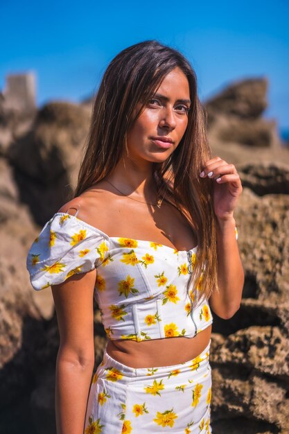 Portret van een jonge vrouw in een witte jurk op het strand aan zee, genietend van de zomer