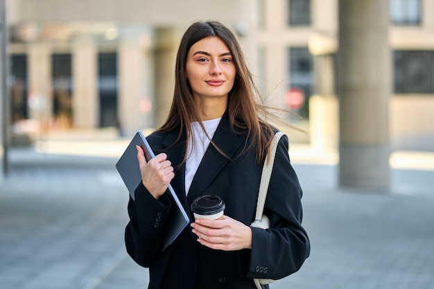 Portret van een jonge vrouw in een zwart pak met een laptop Kantoormedewerker freelancer en blogger