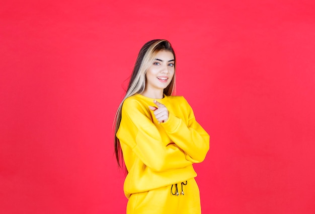 Portret van een jonge vrouw in gele outfit die ergens naar wijst?