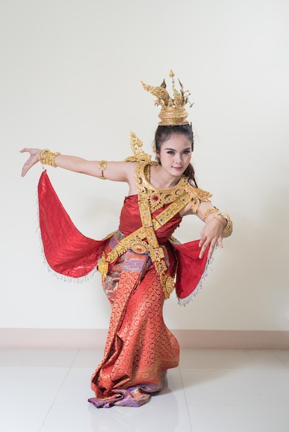 Foto portret van een jonge vrouw in traditionele kleding die tegen de muur danst