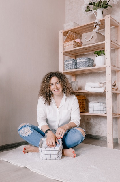 Portret van een jonge vrouw in vrijetijdskleding die prachtig dingen in containers en dozen stopt. het concept van een goede opslag van accessoires en ondergoed in de kast