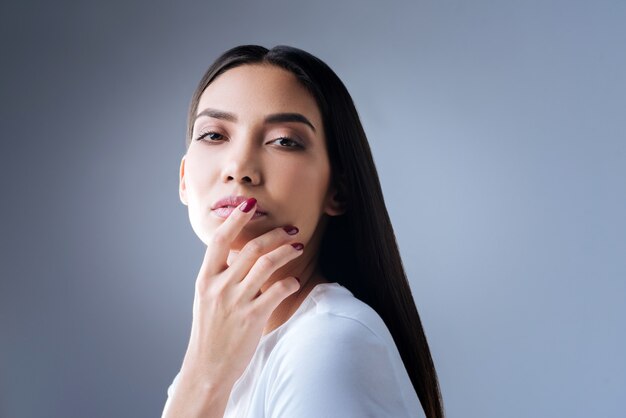 portret van een jonge vrouw in wit t-shirt poseren tegen een grijze muur