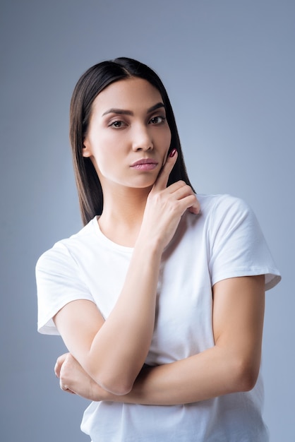 portret van een jonge vrouw in wit t-shirt poseren tegen een grijze muur