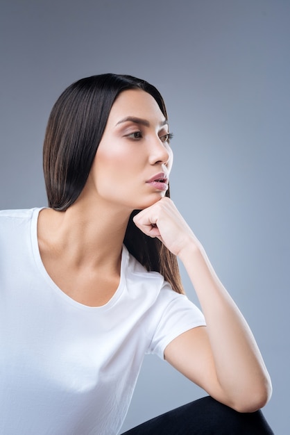 portret van een jonge vrouw in wit t-shirt poseren tegen een grijze muur