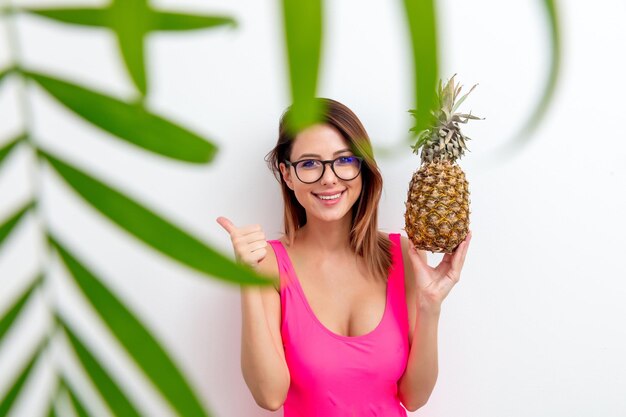 Portret van een jonge vrouw in zwembroek en bril met ananas op witte achtergrond. Zomerseizoen afbeelding concept