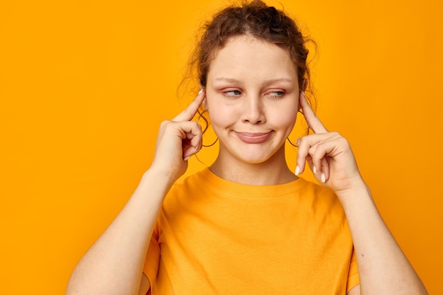 Portret van een jonge vrouw leuke oorbellen grimas handgebaar jeugd stijl gele achtergrond ongewijzigd