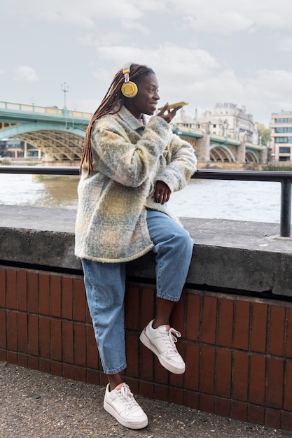 Foto portret van een jonge vrouw met afro-dreadlocks en koptelefoon in de stad