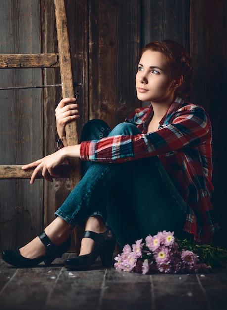 Portret van een jonge vrouw met bloemen op houten achtergrond