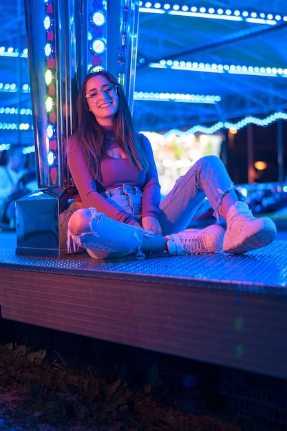 Portret van een jonge vrouw met bril verlicht door de lichten van een kermis