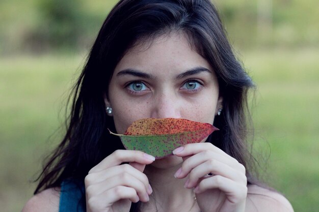 Portret van een jonge vrouw met een blad terwijl ze buiten staat