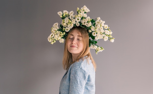 Portret van een jonge vrouw met een boeket rozen op een grijze achtergrond